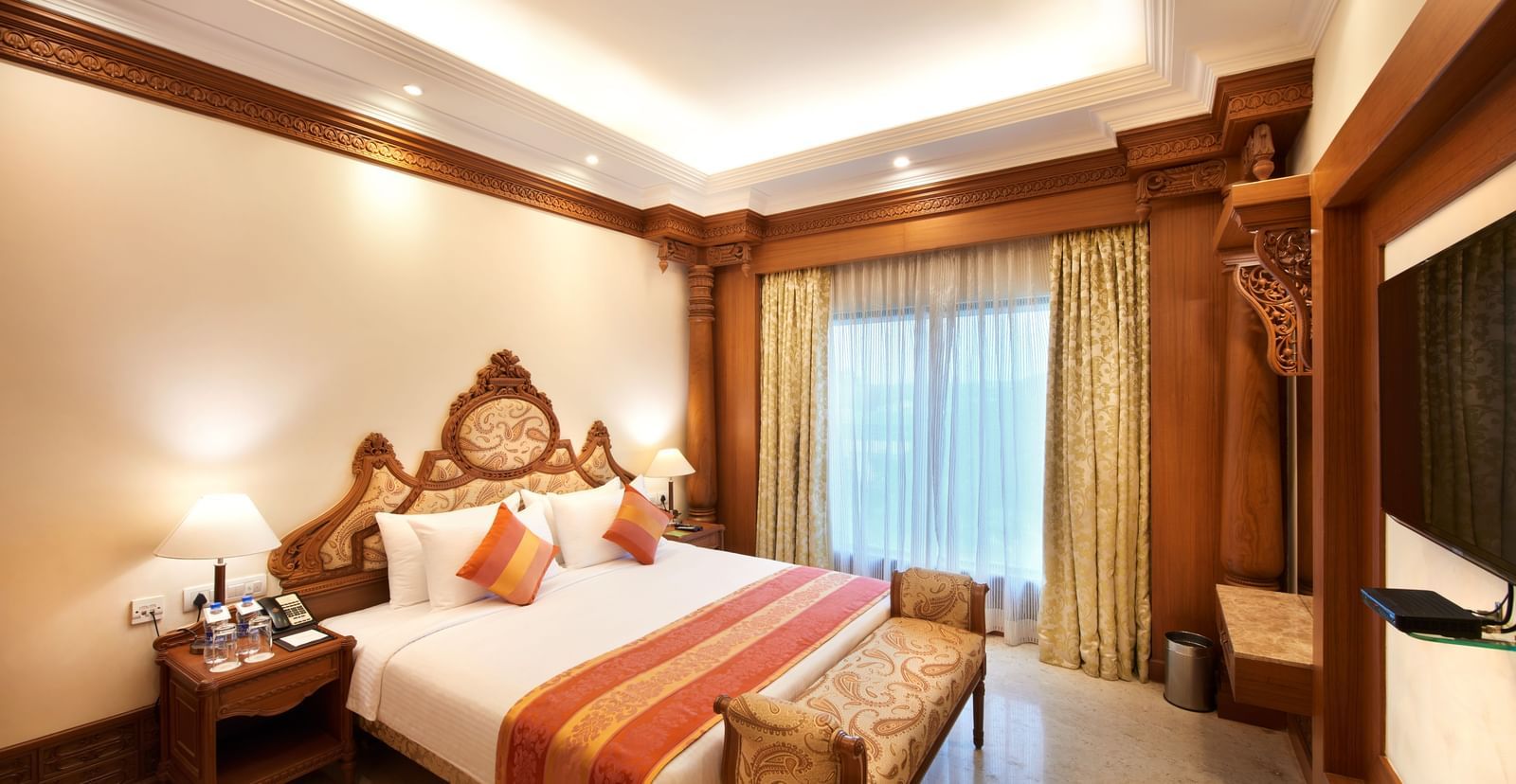 An image of a bedroom at Accord Puducherry featuring a bed, flat TV screen on the wall, and a cabinet 